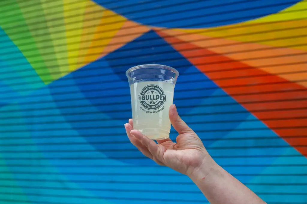 Hand holding a bullpen cup in downtown Durham.