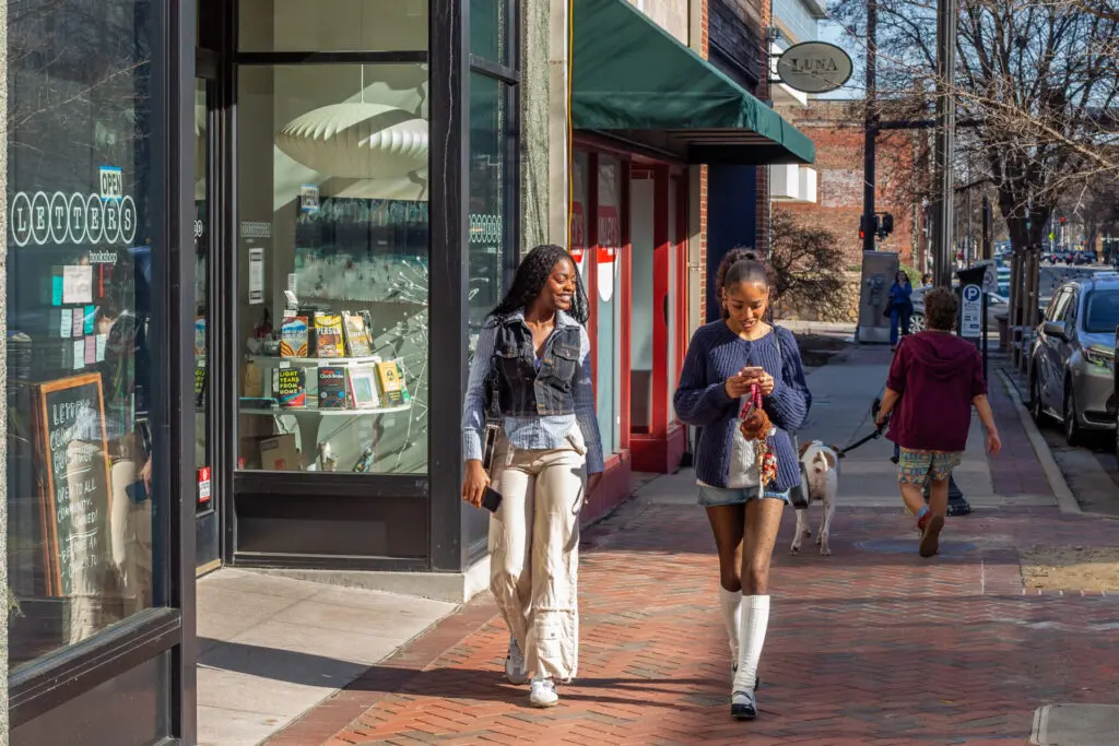 Two young smiling women walking down street in downtown Durham.