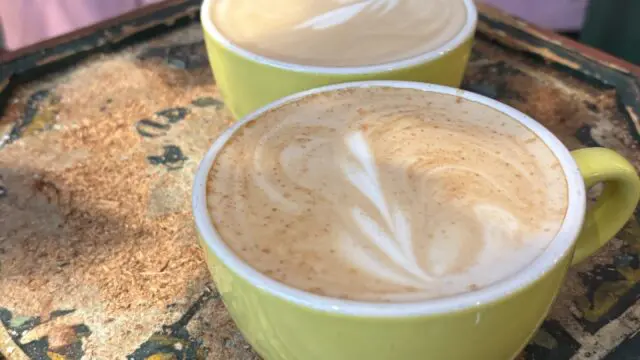 two hot lattes with latte art in yellow mugs