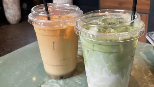 strawberry matcha and iced latte sitting on green marble table