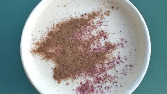 hot rose chai with cardamom powder sitting on green table