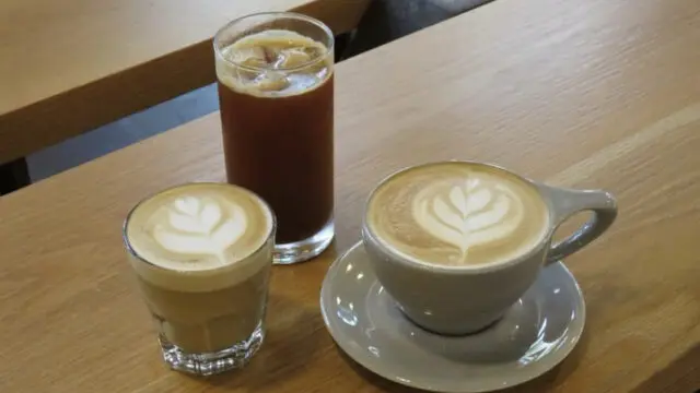 Latte, Cortado, Iced Americano sitting on wood table