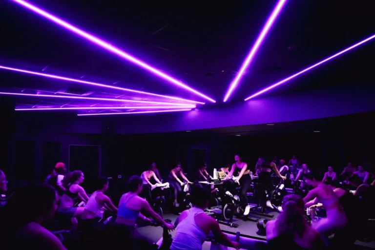 People cycling in a studio with bright lights in dark room